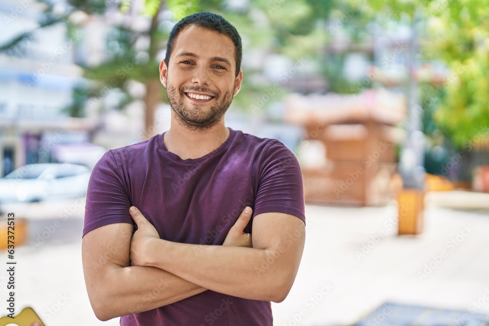 Young man smiling confident standing with arms crossed gesture at park