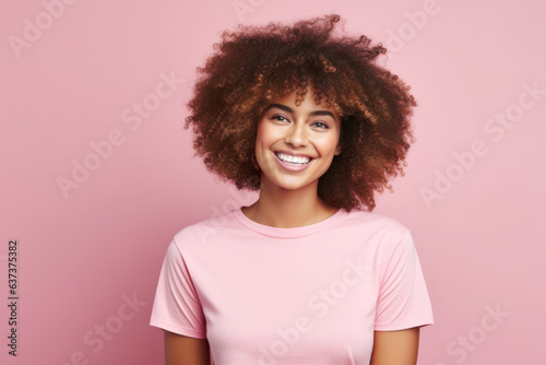 Beautiful woman with afro hair smiling on bright pink background, smiling portrait