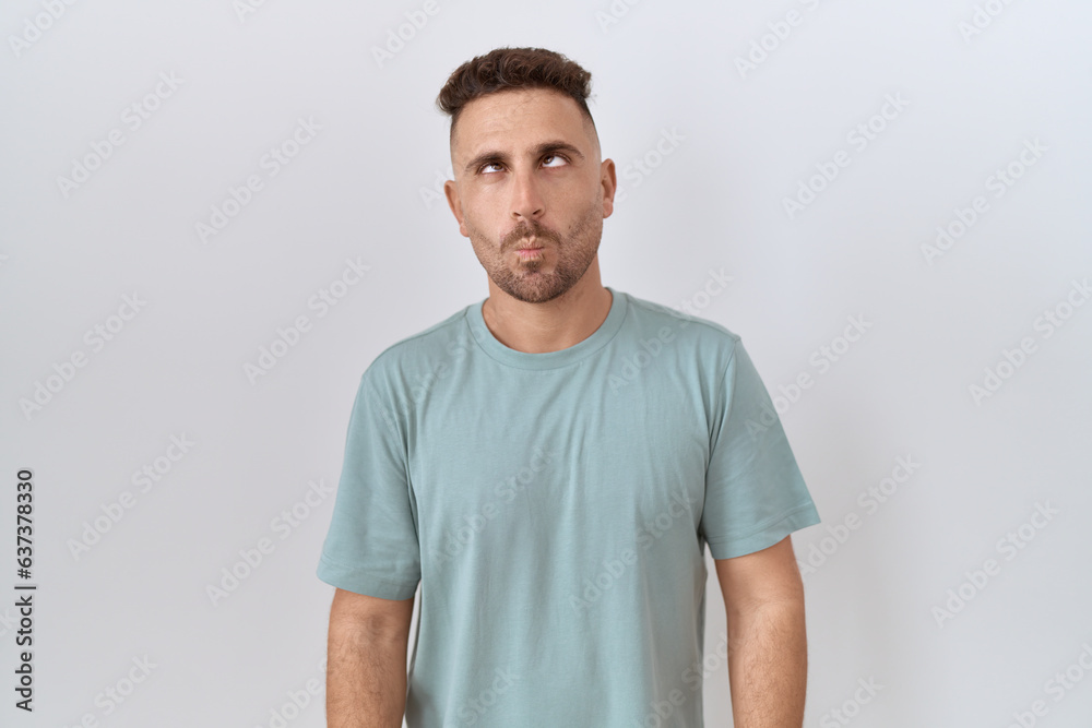 Hispanic man with beard standing over white background making fish face with lips, crazy and comical gesture. funny expression. Hispanic man with beard standing over white background making fish face with lips, crazy and comical gesture. funny expression.