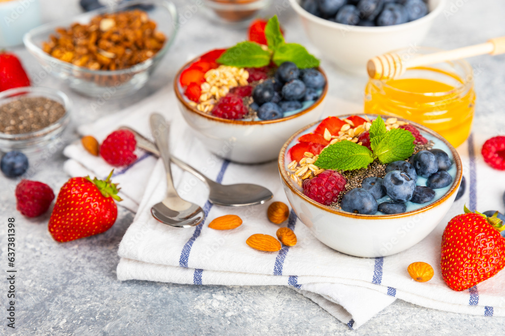 Bowl of granola with yogurt and fresh berries on a texture table. Yogurt berries, acai bowl, spirulina bowl. Healthy food, balanced breakfast. Strawberries, blueberries, kiwi, peach, almonds and chia. Bowl of granola with yogurt and fresh berries on a texture table. Yogurt berries, acai bowl, spirulina bowl. Healthy food, balanced breakfast. Strawberries, blueberries, kiwi, peach, almonds and chia.