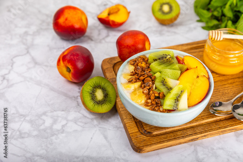 Bowl of granola with yogurt and fresh berries on a texture table. Yogurt berries, acai bowl, spirulina bowl. Healthy food, balanced breakfast. Strawberries, blueberries, kiwi, peach, almonds and chia.