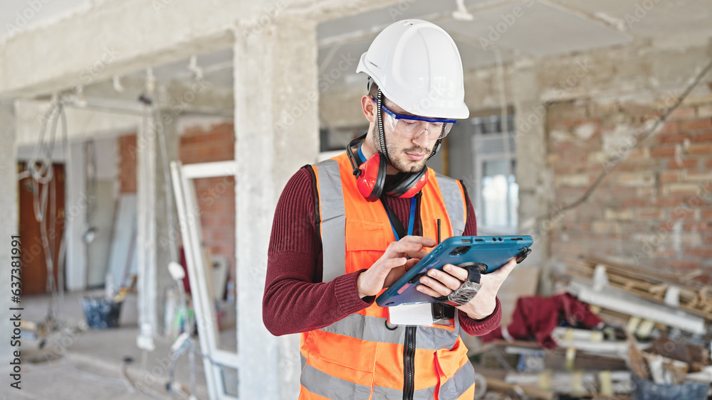 Young hispanic man builder using touchpad at construction site Young hispanic man builder using touchpad at construction site