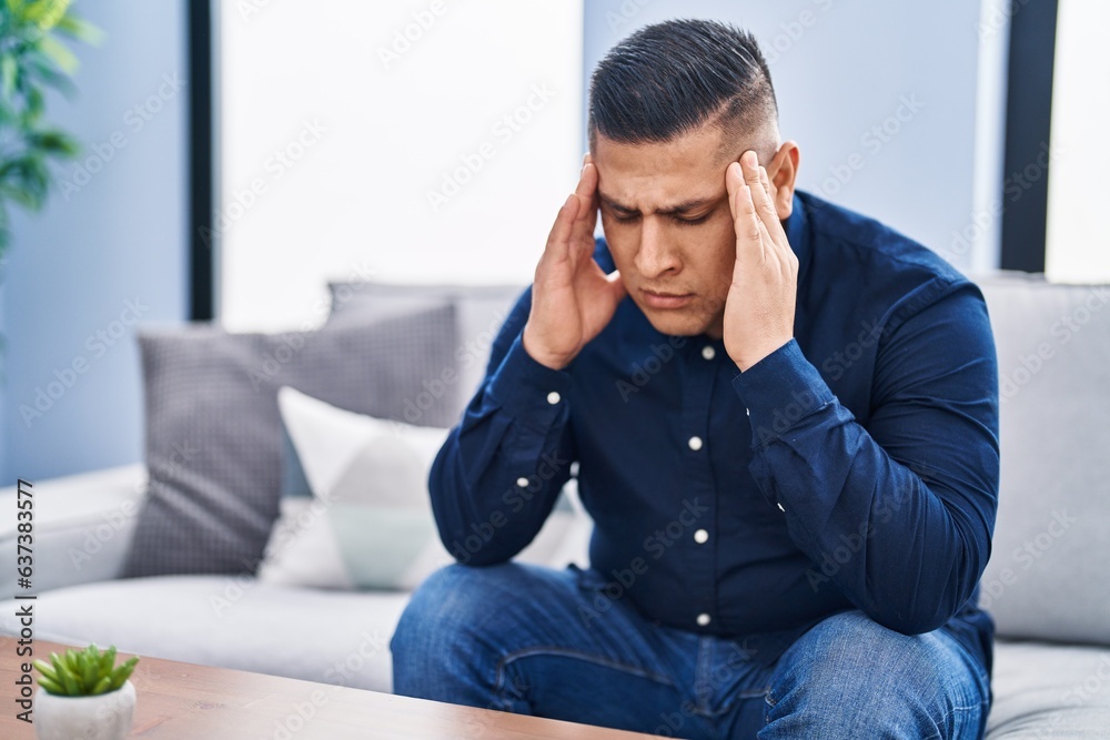 Young latin man stressed sitting on sofa at home