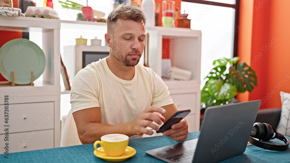 Young man using smartphone sitting on table at dinning room Young man using smartphone sitting on table at dinning room