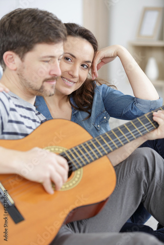 couple playing guitar on couch indoor