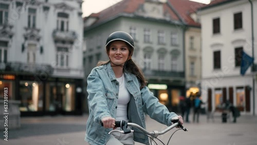 Waist up portrait view of beautiful young woman riding bicycle along the street and smiling photo