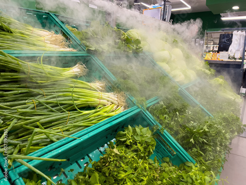 Fotografi Greens in the vegetable aisle sprayed with water to keep them fresh and alive in