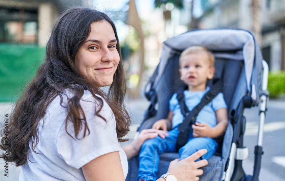 Obraz premium Mother and son smiling confident sitting on stroller baby at street