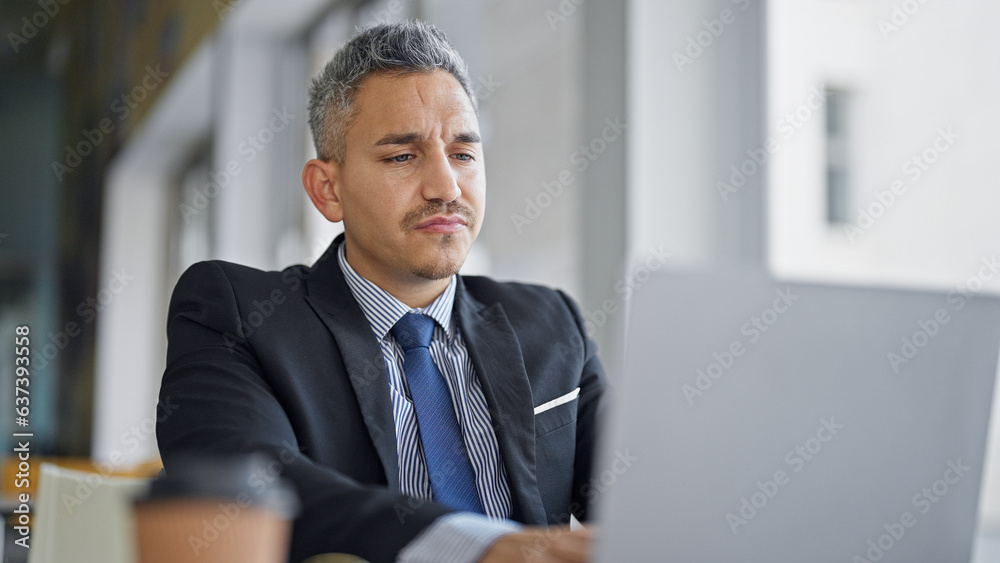 Fototapeta premium Young hispanic man business worker using laptop at office