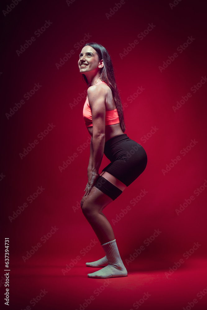 Young sportive attractive caucasian athlete woman posing in pink tank top and black sauna shorts fitness outfit. Studio shooting with pretty slim fit brunette doing aerobic stretching with rubberbands Young sportive attractive caucasian athlete woman posing in pink tank top and black sauna shorts fitness outfit. Studio shooting with pretty slim fit brunette doing aerobic stretching with rubberbands