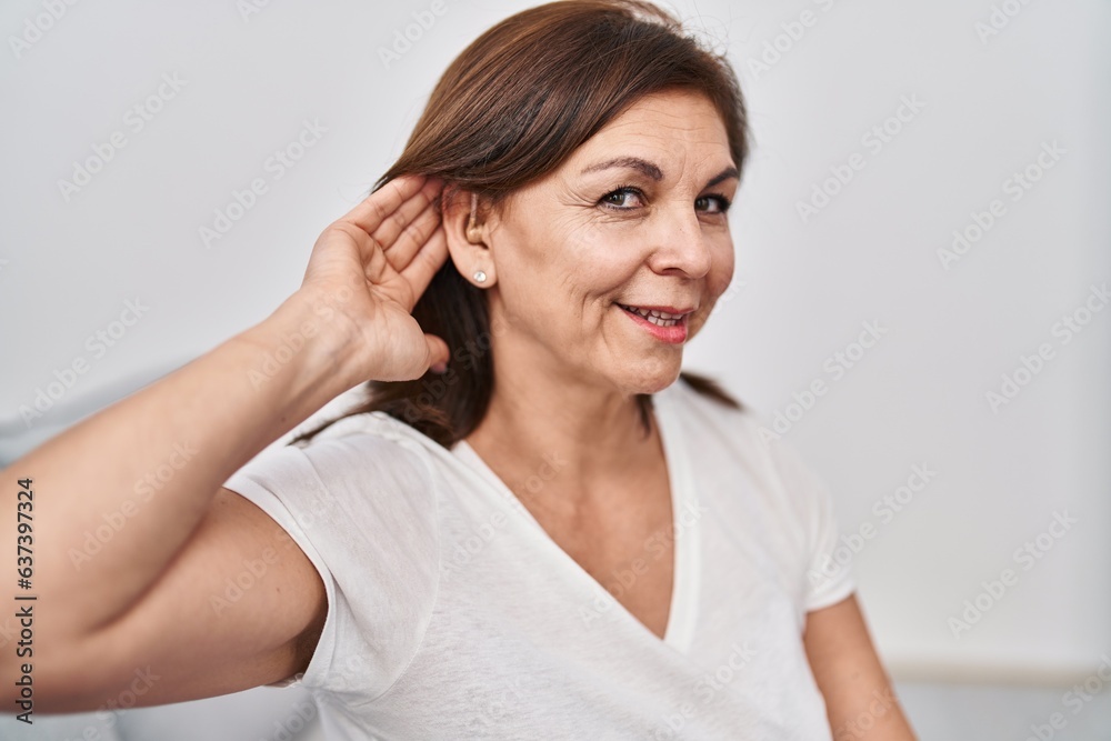 Middle age woman smiling confident using hearing aid at home Middle age woman smiling confident using hearing aid at home