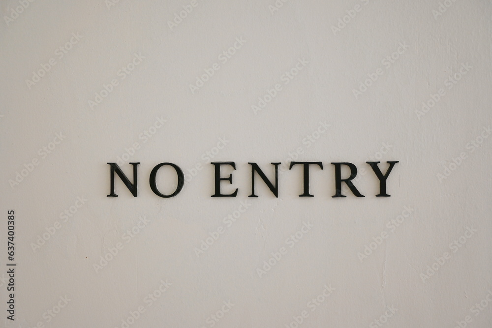 The NO ENTRY sign is installed on the cream-coloured cement wall to inform those involved. The letters NO are circled in white (blurred) and ENTRY in black letters. Black steel letters on ement wall
The NO ENTRY sign is installed on the cream-coloured cement wall to inform those involved. The letters NO are circled in white (blurred) and ENTRY in black letters. Black steel letters on ement wall