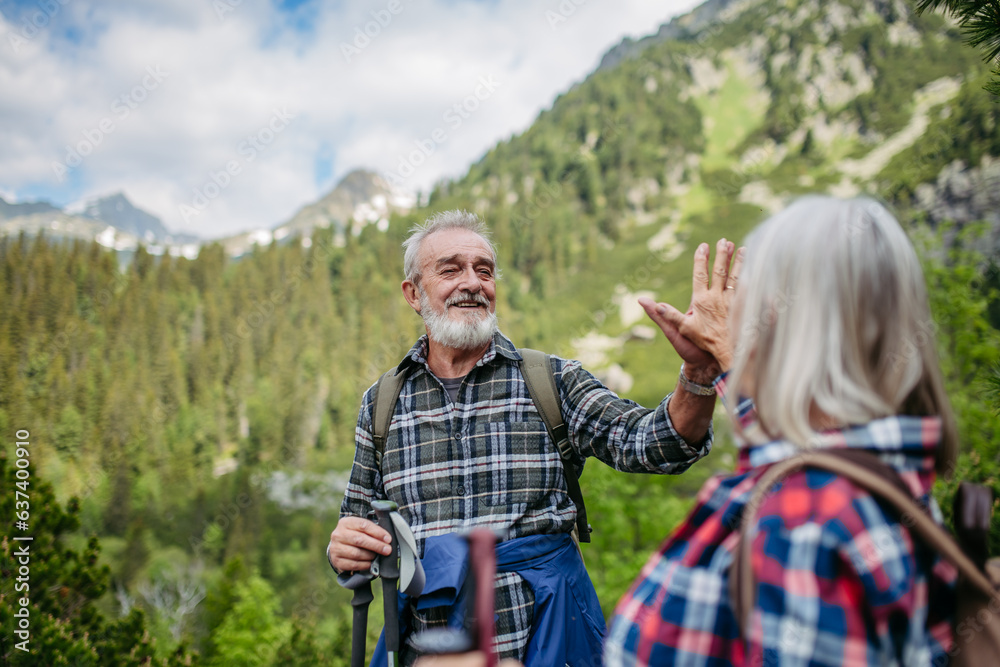 Portrait of senior man giving high five to his wife after successful hike in autumn mountains.