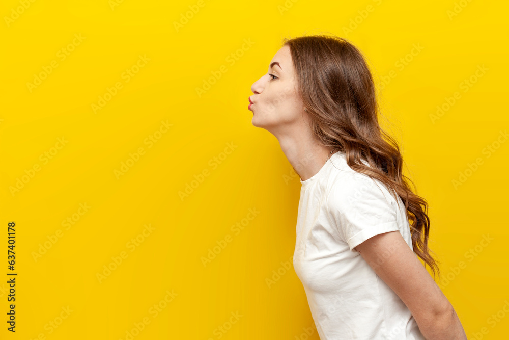 young cute girl sends air kiss to the side on yellow isolated background, woman flirts and shows gesture of romance young cute girl sends air kiss to the side on yellow isolated background, woman flirts and shows gesture of romance