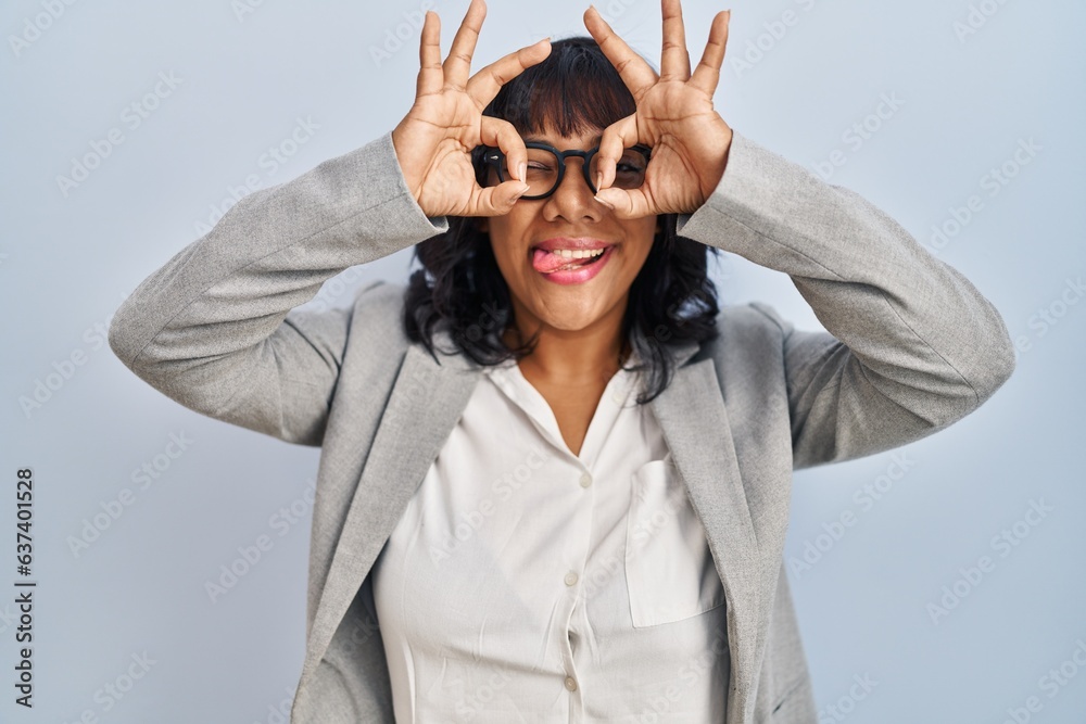 Hispanic woman standing over isolated background doing ok gesture like binoculars sticking tongue out, eyes looking through fingers. crazy expression. Hispanic woman standing over isolated background doing ok gesture like binoculars sticking tongue out, eyes looking through fingers. crazy expression.