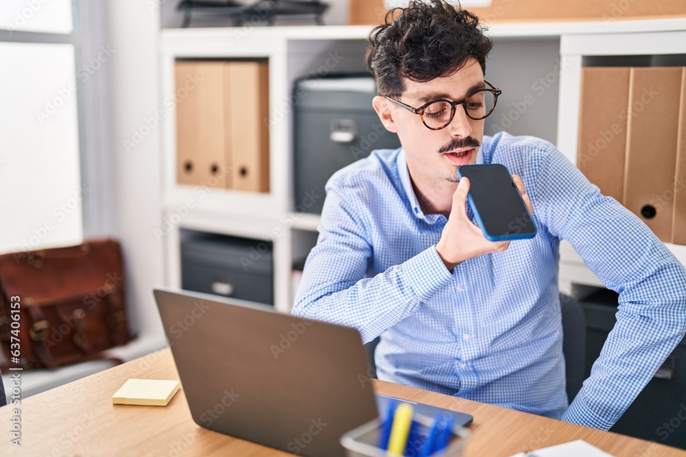 Young caucasian man business worker using laptop talking on smartphone at office Young caucasian man business worker using laptop talking on smartphone at office