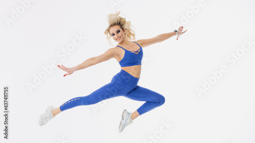 A young female cheerleader jumps on a white isolated background. Bright makeup, stylish tracksuit