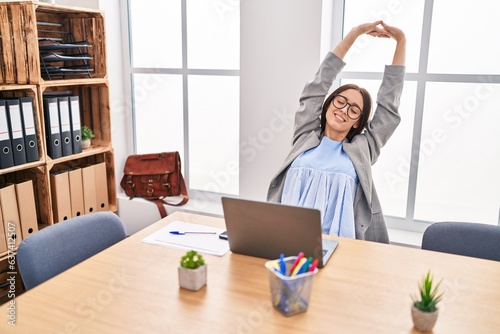 Young beautiful hispanic woman business worker relaxed stretching arms at office © Krakenimages.com