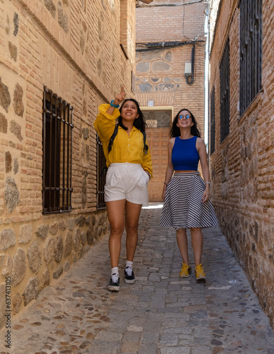 Two women friends exploring the medieval city of Toledo in Spain. Tourists walking through the narrow streets.