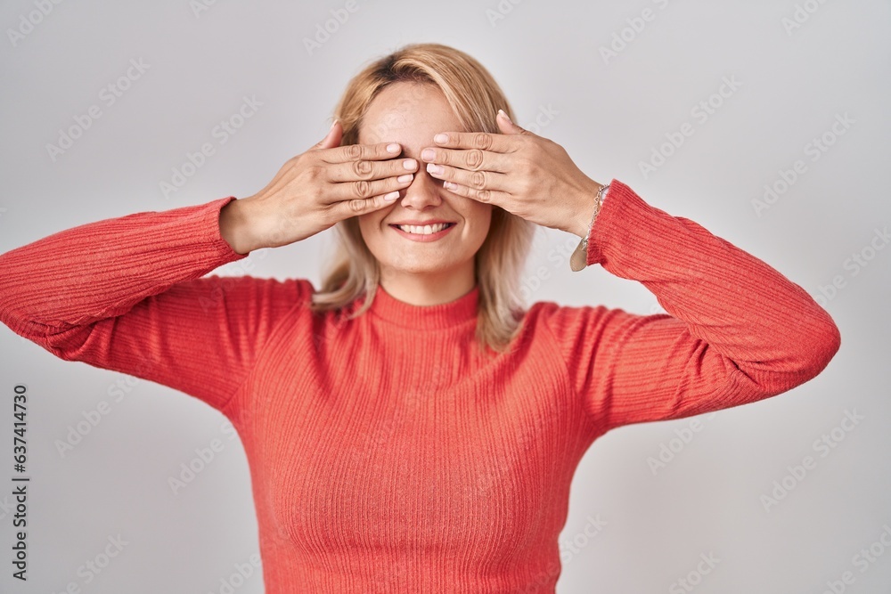 Φωτογραφία Blonde woman standing over isolated background covering eyes with hands smiling cheerful and funny