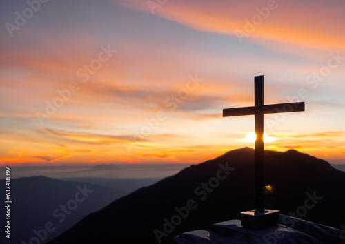 A Christian cross on a mountain at sunset.