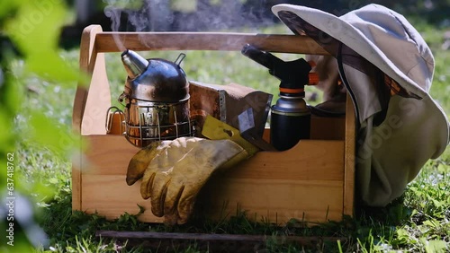 The apiary and honey making, small agricultural business and hobby. Using smoker to calm bees in a beehive.