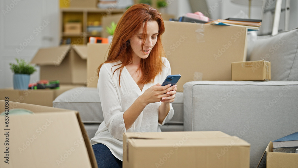 Young redhead woman using smartphone at new home Young redhead woman using smartphone at new home