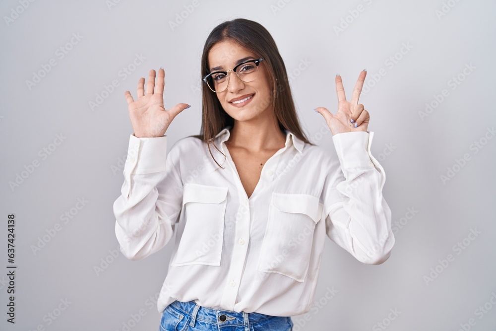 Young brunette woman wearing glasses showing and pointing up with fingers number eight while smiling confident and happy. Young brunette woman wearing glasses showing and pointing up with fingers number eight while smiling confident and happy.