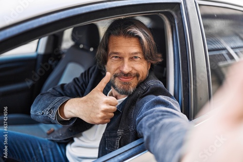 Middle age man make selfie by camera doing ok gesture at street