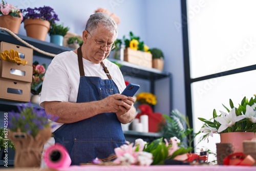 Middle age grey-haired man florist smiling confident using smartphone at florist