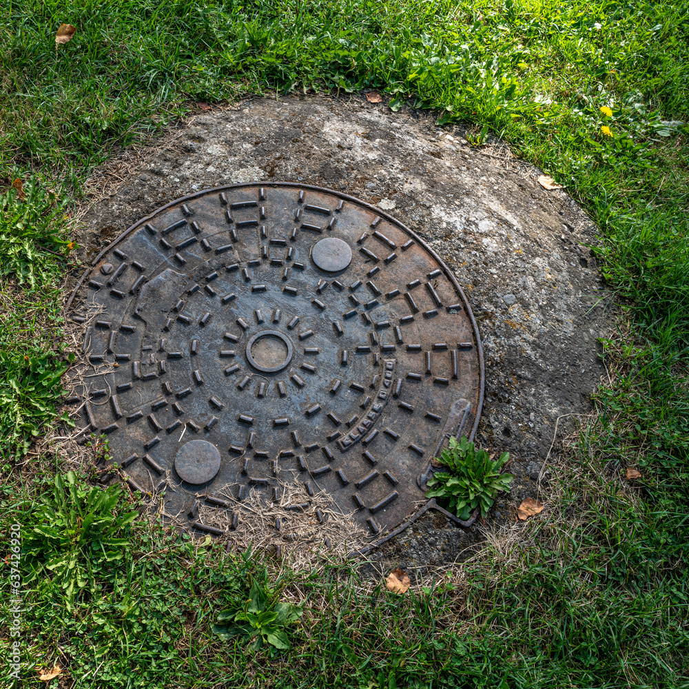 plaque d'égout ronde sur une pelouse verte