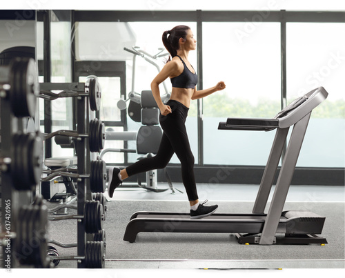 Young female in black leggings running on a treadmill at a gym