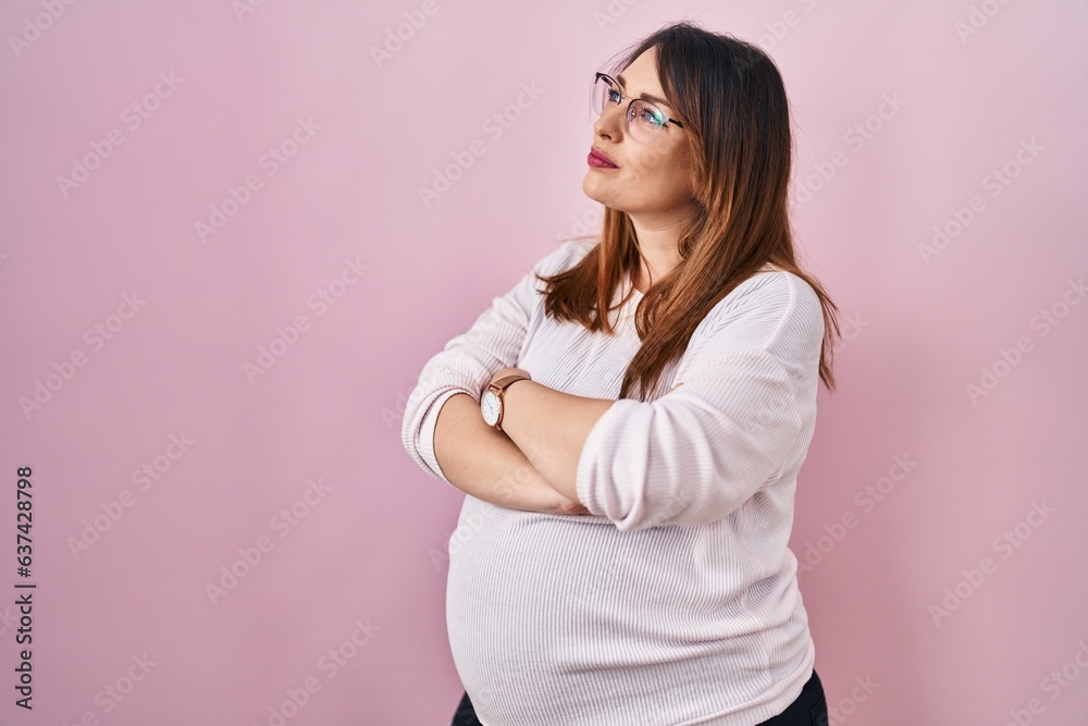 Pregnant woman standing over pink background looking to the side with arms crossed convinced and confident Pregnant woman standing over pink background looking to the side with arms crossed convinced and confident