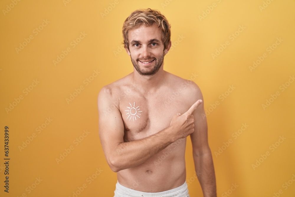 Caucasian man standing shirtless wearing sun screen cheerful with a smile on face pointing with hand and finger up to the side with happy and natural expression