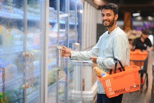 Photography Portrait of handsome young Indian man standing at grocery shop or supermarket, Closeup
