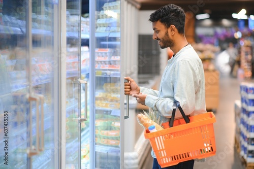 Photography Portrait of handsome young Indian man standing at grocery shop or supermarket, Closeup