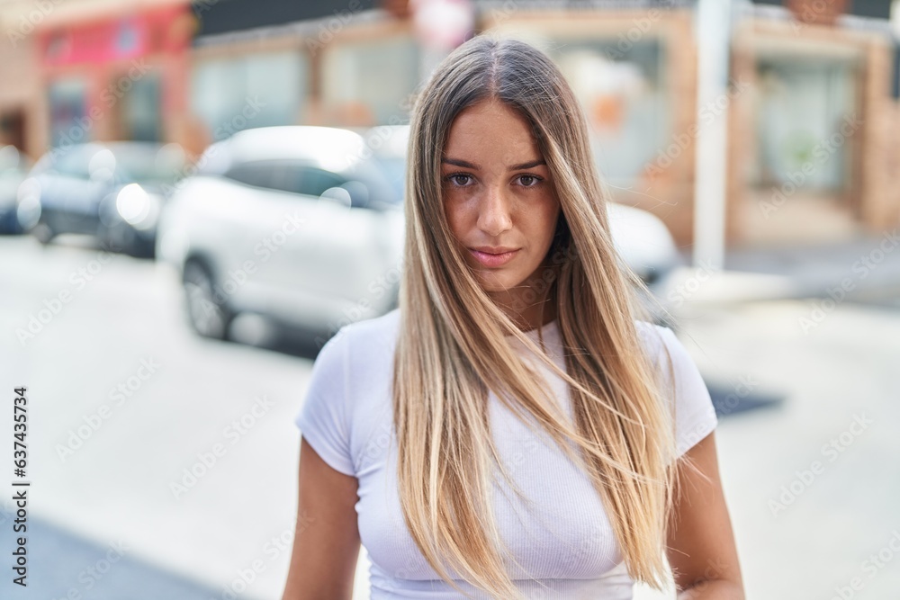 Young beautiful hispanic woman looking to the camera with serious expression at street