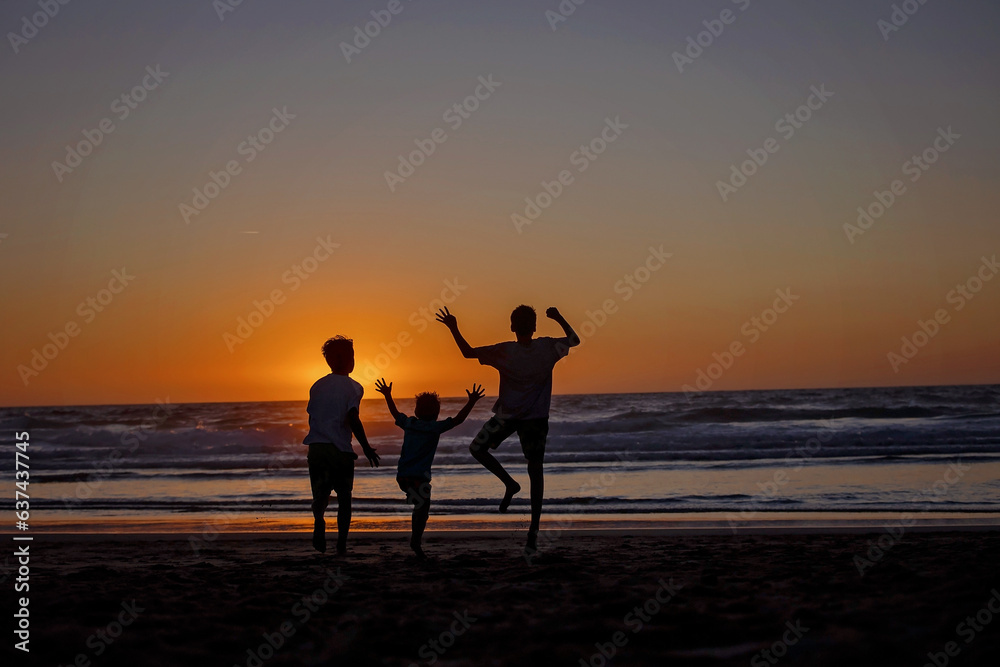 Happy children, boys, playing on the beach on sunset, kid cover in sand, smiling, laughing Happy children, boys, playing on the beach on sunset, kid cover in sand, smiling, laughing
