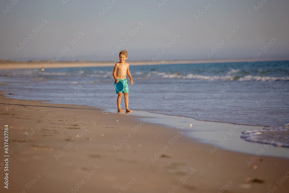 Happy children, boys, playing on the beach on sunset, kid cover in sand, smiling, laughing Happy children, boys, playing on the beach on sunset, kid cover in sand, smiling, laughing
