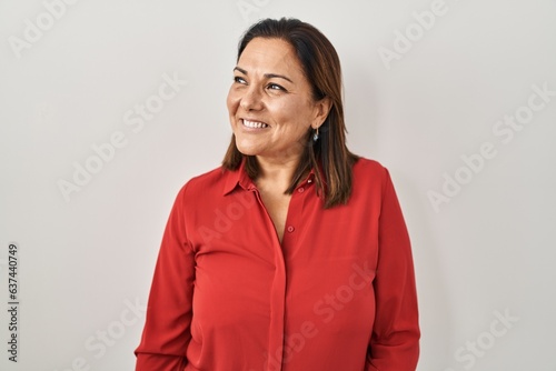 Foto Hispanic mature woman standing over white background looking away to side with smile on face, natural expression