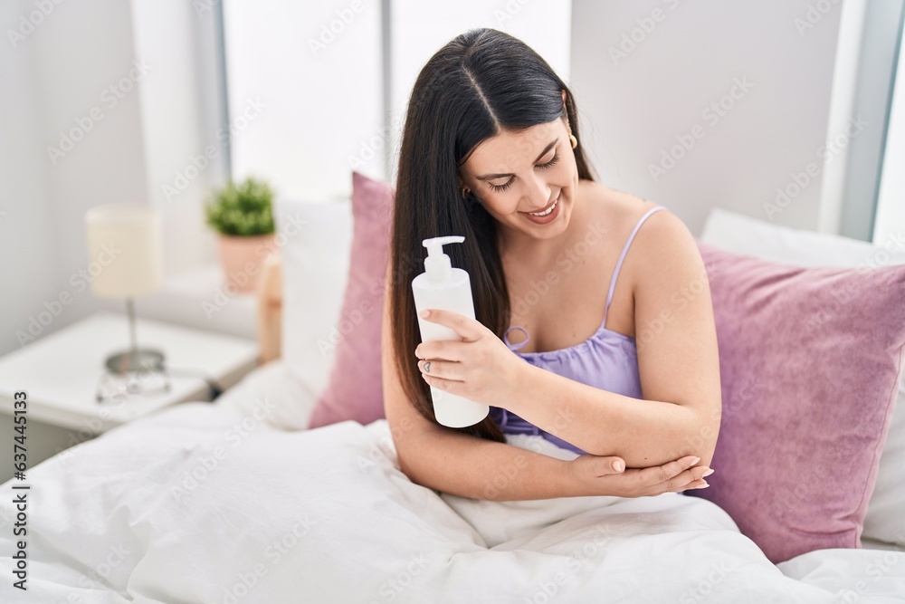 Young hispanic woman applying skin treatment sitting on bed at bedroom Young hispanic woman applying skin treatment sitting on bed at bedroom