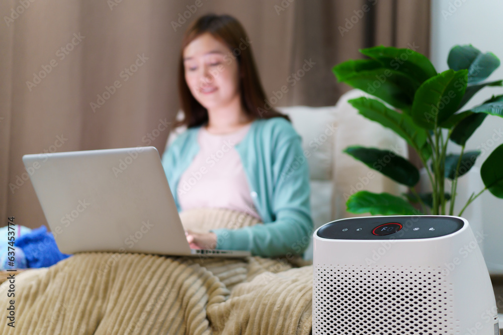 Φωτογραφία Happy Asian young woman turning on high efficiency air purifier while staying and relaxing in the living room