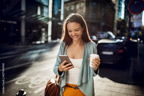 Young woman using a smart phone while walking on a sidewalk in the city