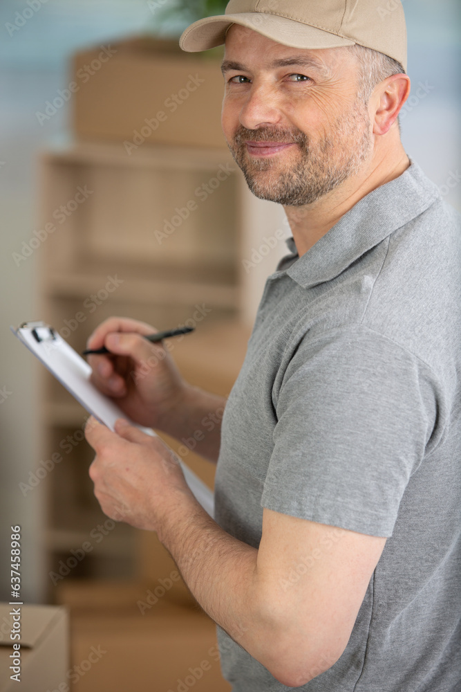 post employee with parcels taking notes on his clipboard post employee with parcels taking notes on his clipboard