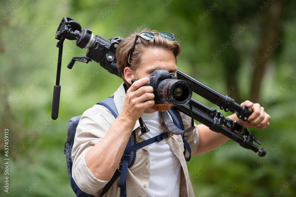 professional photographer with cdslr and tripod in forest