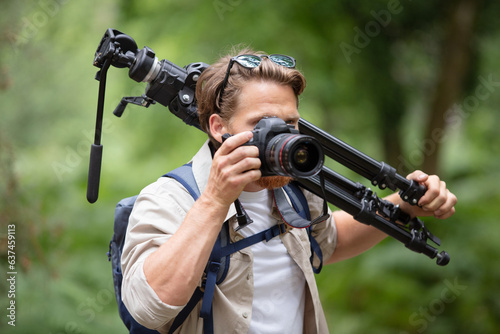 professional photographer with cdslr and tripod in forest