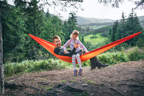 happy father with daughter on hammock mountains on background