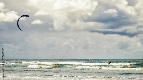 kite surfing on the beach with faming waves en clouded skies