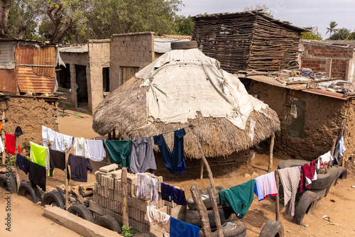 Traditional Thatched Hut with Mud Walls and Thatched Roof, Enclosed by Tire and Wire Fence