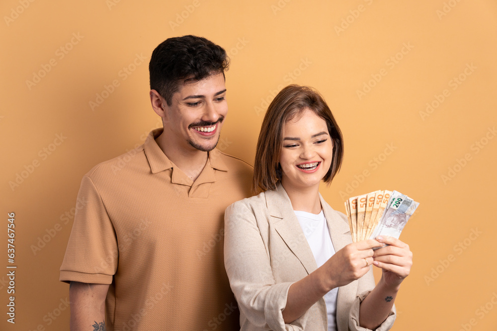 happy couple looking at brazilian money cash in beige background. economy, payment, successful concept. happy couple looking at brazilian money cash in beige background. economy, payment, successful concept.